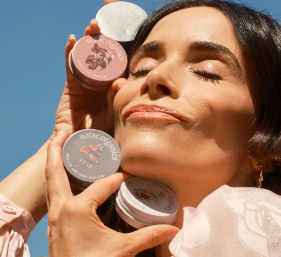 Abigail Spencer holding Norse Organics jars against a blue sky